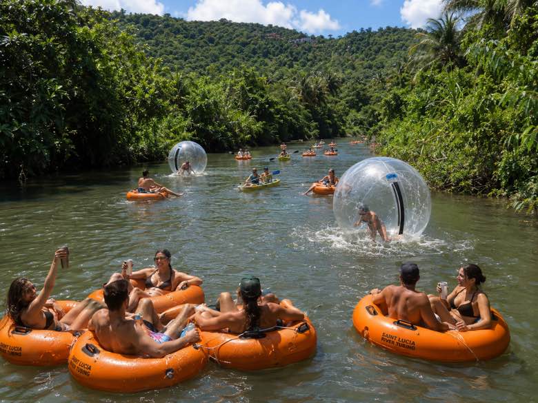 Guests relaxing in branded Saint Lucia River Tubing tubes with water balls behind them