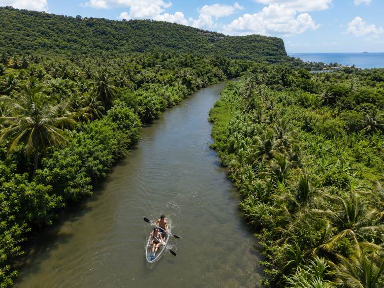 Two guests paddling a transparent kayak down the Roseau River