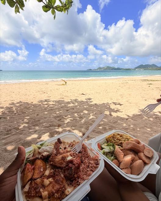 Two creole lunch boxes held up in front of the sea