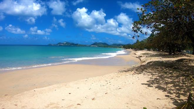 Shaded sand and calm turquoise water at Roseau Beach